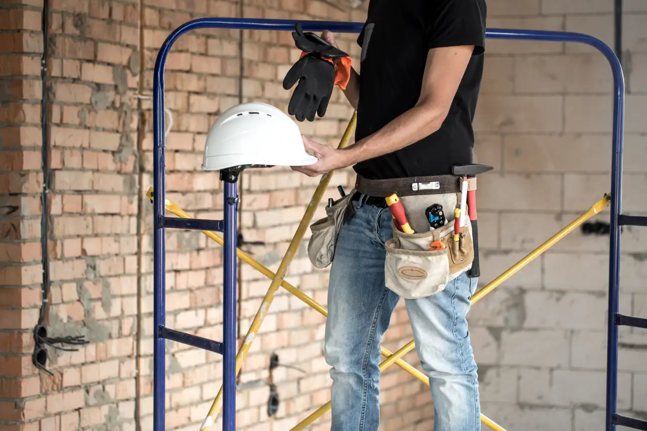 Craftsman in a workshop with a hard hat in hand